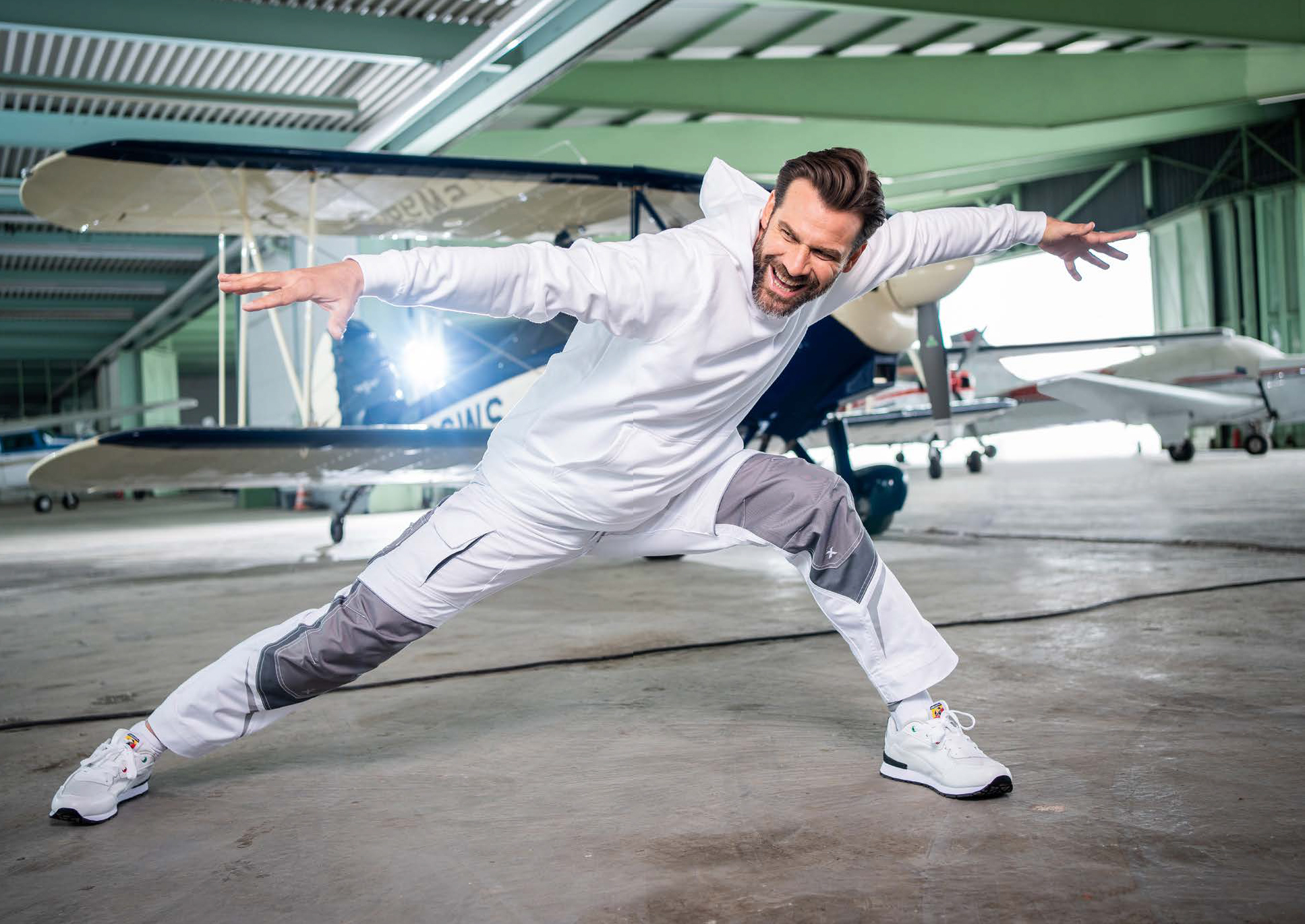Mann mit SuperStretch Bundhose im Flugzeughangar vor sportflugzeug