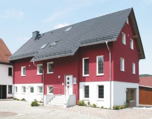 Haus mit dunklem Dach, dunkelroter Fassade und wei&szlig;em Sockel