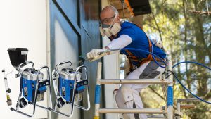 Maler mit PSA spritz anthrazite Farbe auf eine Wand - Abbildung der Airlessger&auml;te GX21 und GX21-Plus