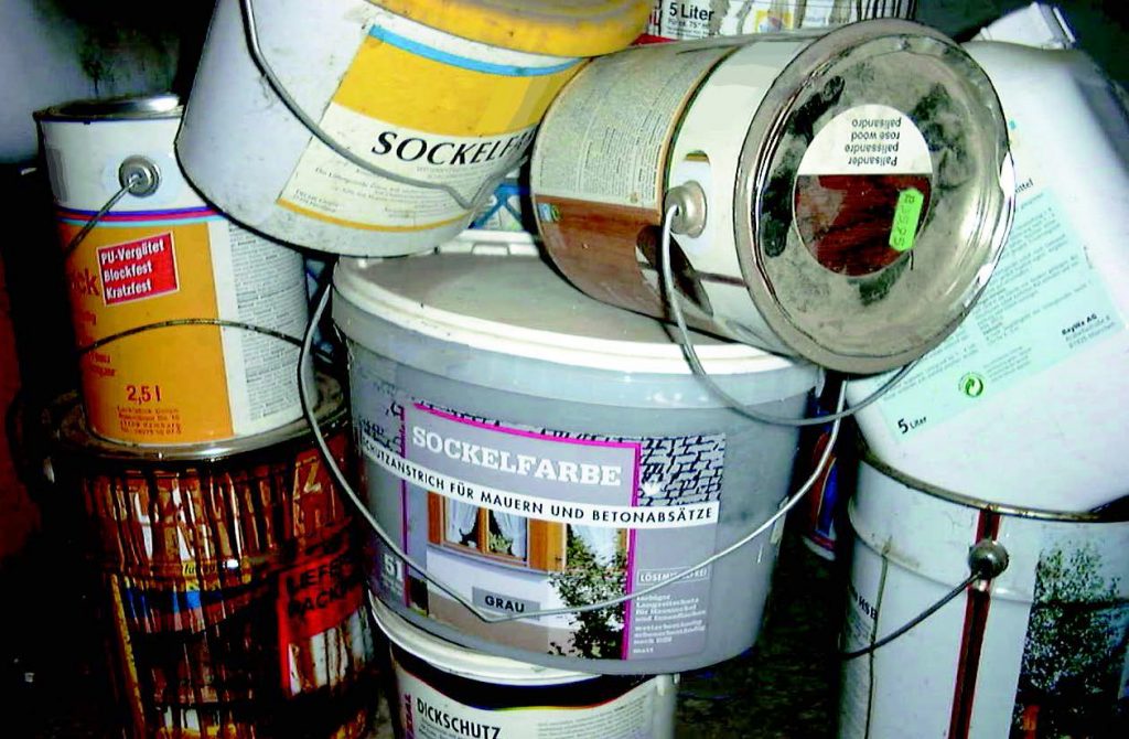 Haufen mit Eimer und Dosen mit Farbresten.