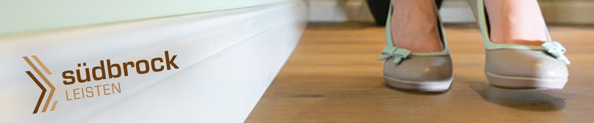 Holtfussboden mit weißer Holzrandleiste - Leisten-Kollektion, Broschüre und Südbrock-Logo im Vordergrund