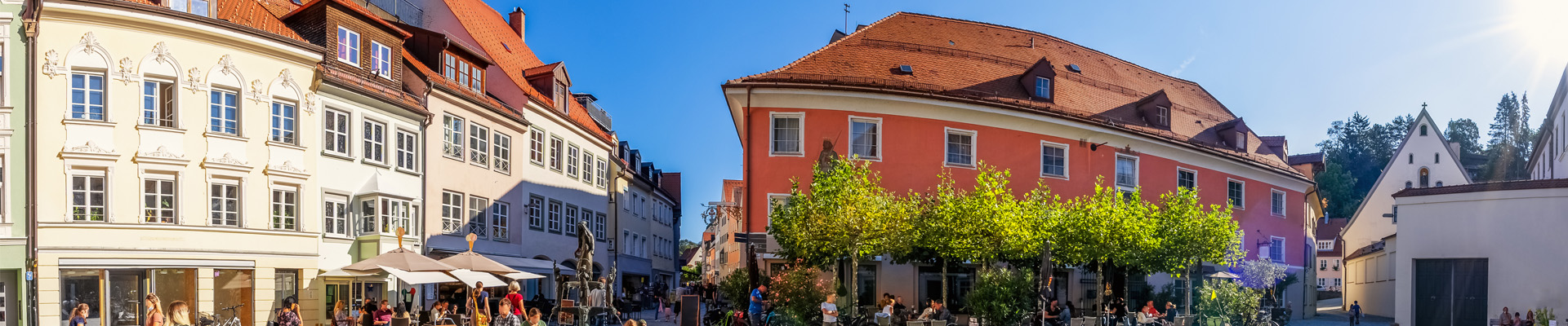 Panoramabild einer Innentstadt mit vielen verschiedenen Fassaden. Menschen in den Straßen.