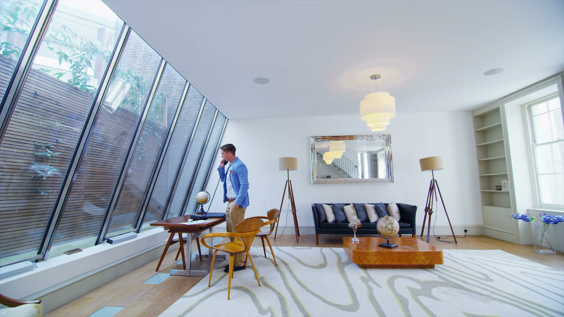 Wohnraum mit riesiger Fensterfront und vielen großen, weißen Flächen - Mann telefoniert